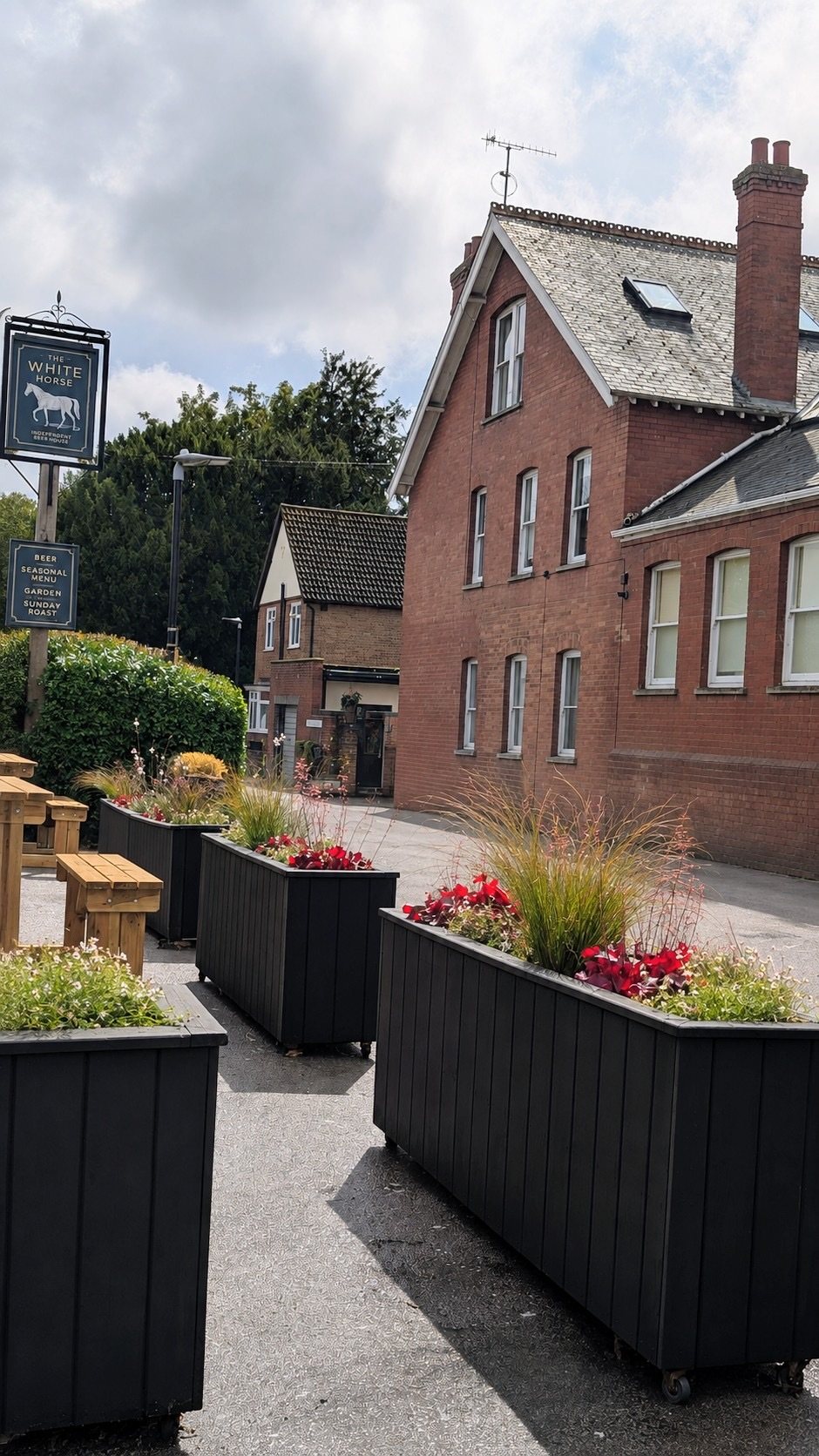 Black timber troughs of grasses and heucheras in the pub garden